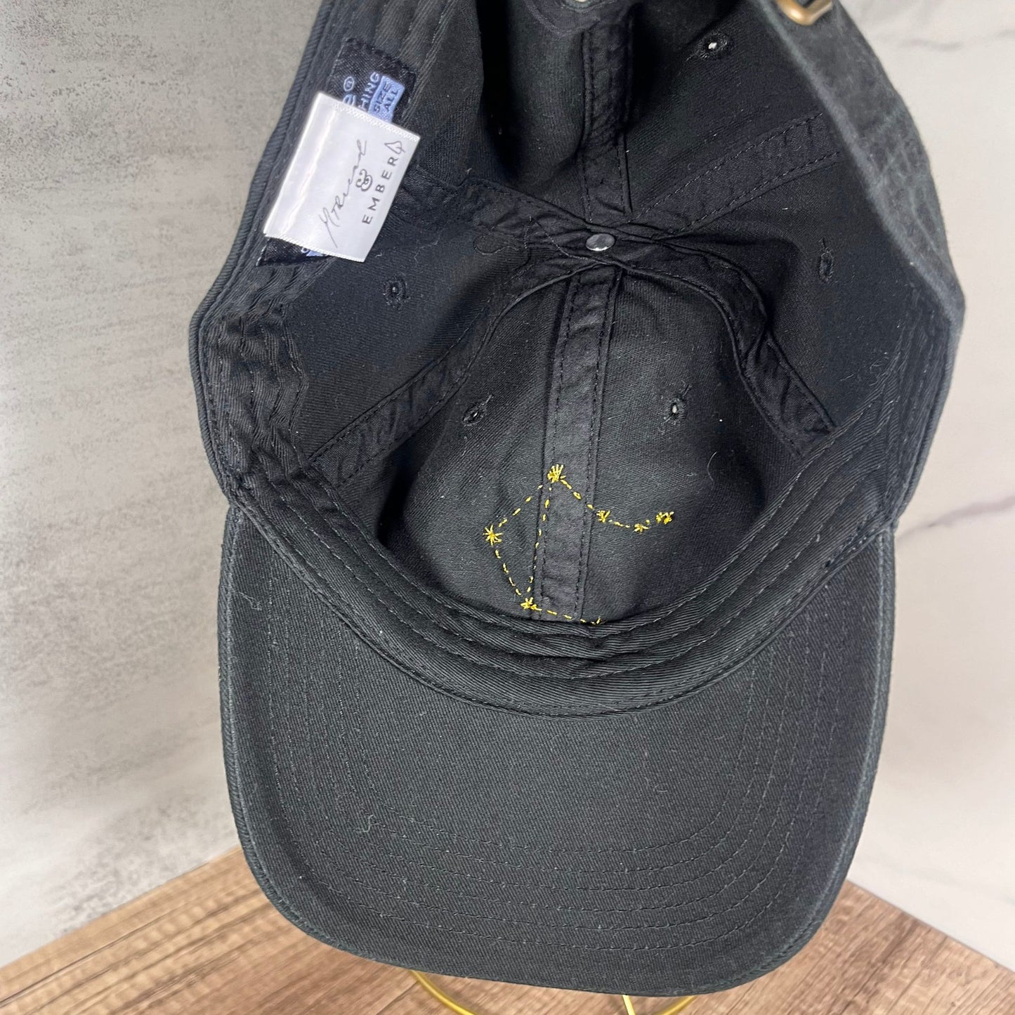 Golden Libra constellation design on the inside of a black adjustable cap.