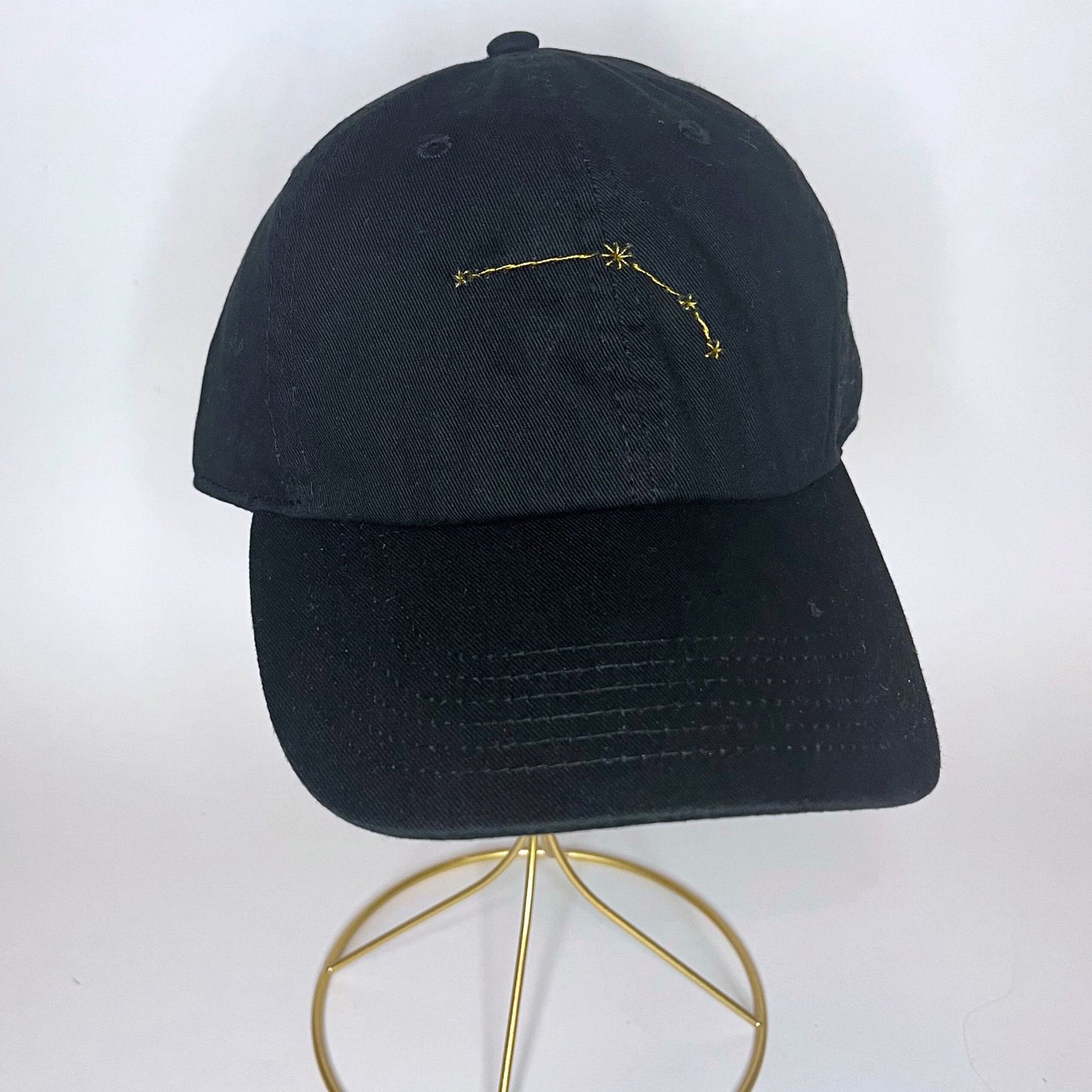 Front view of the black Aries constellation baseball cap with intricate gold hand embroidery.