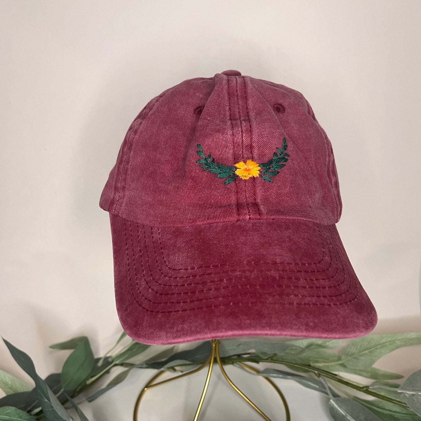 Burgundy baseball hat front view showcasing vibrant floral laurel embroidery.