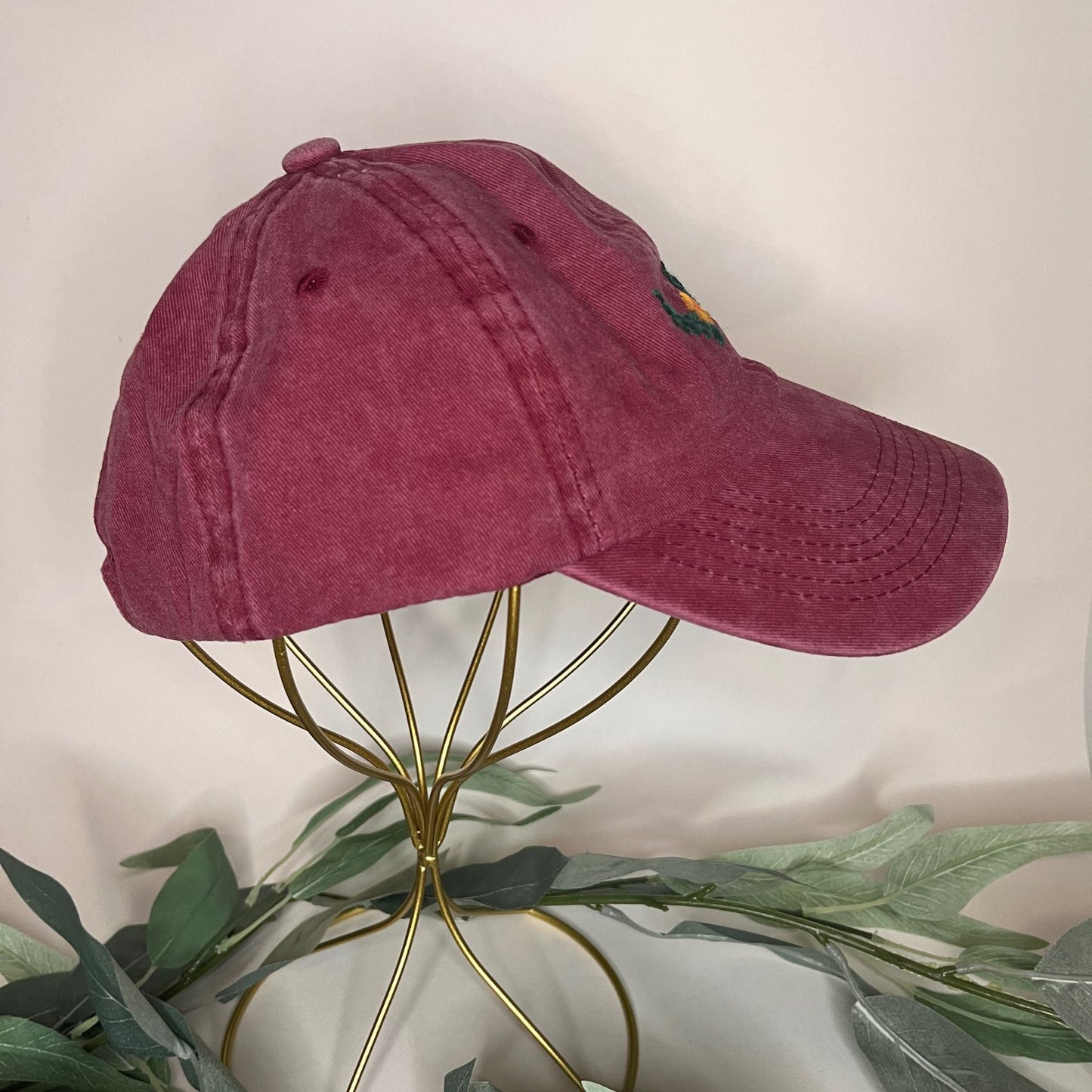 Right-side view of burgundy baseball hat highlighting floral laurel embroidery.