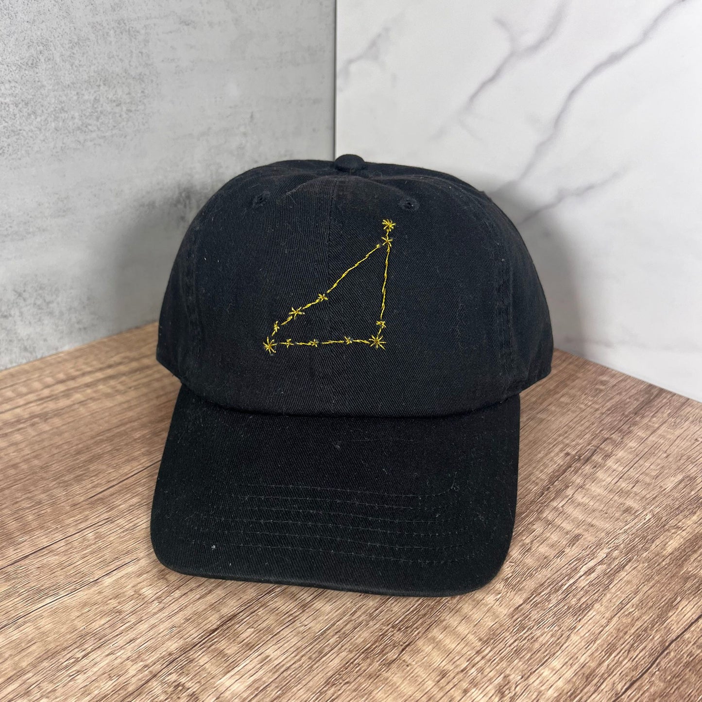 Flat-lay view of black Cancer constellation hat showcasing intricate embroidery