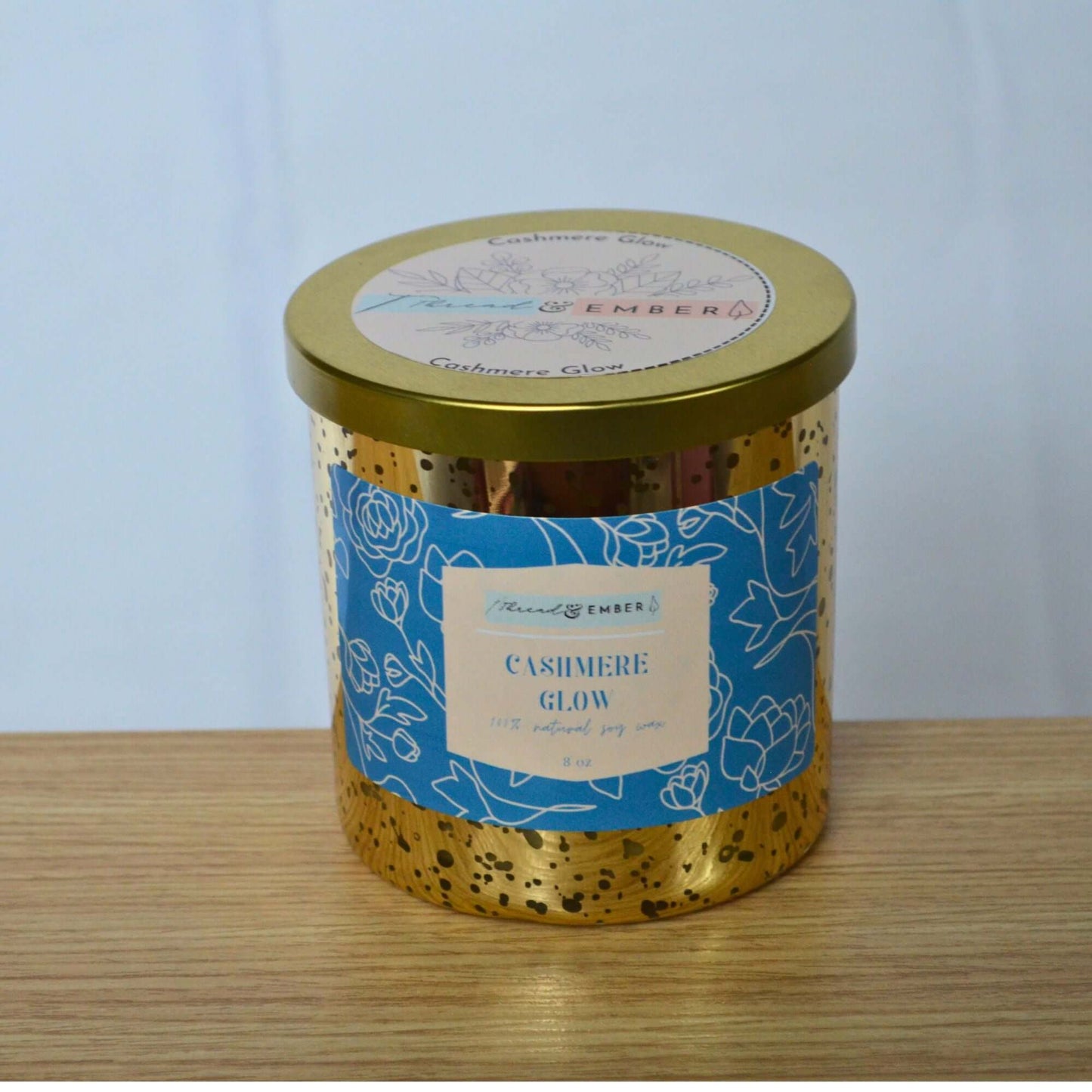 Thread & Ember Cashmere Glow candle in gold mercury glass with blue floral label.