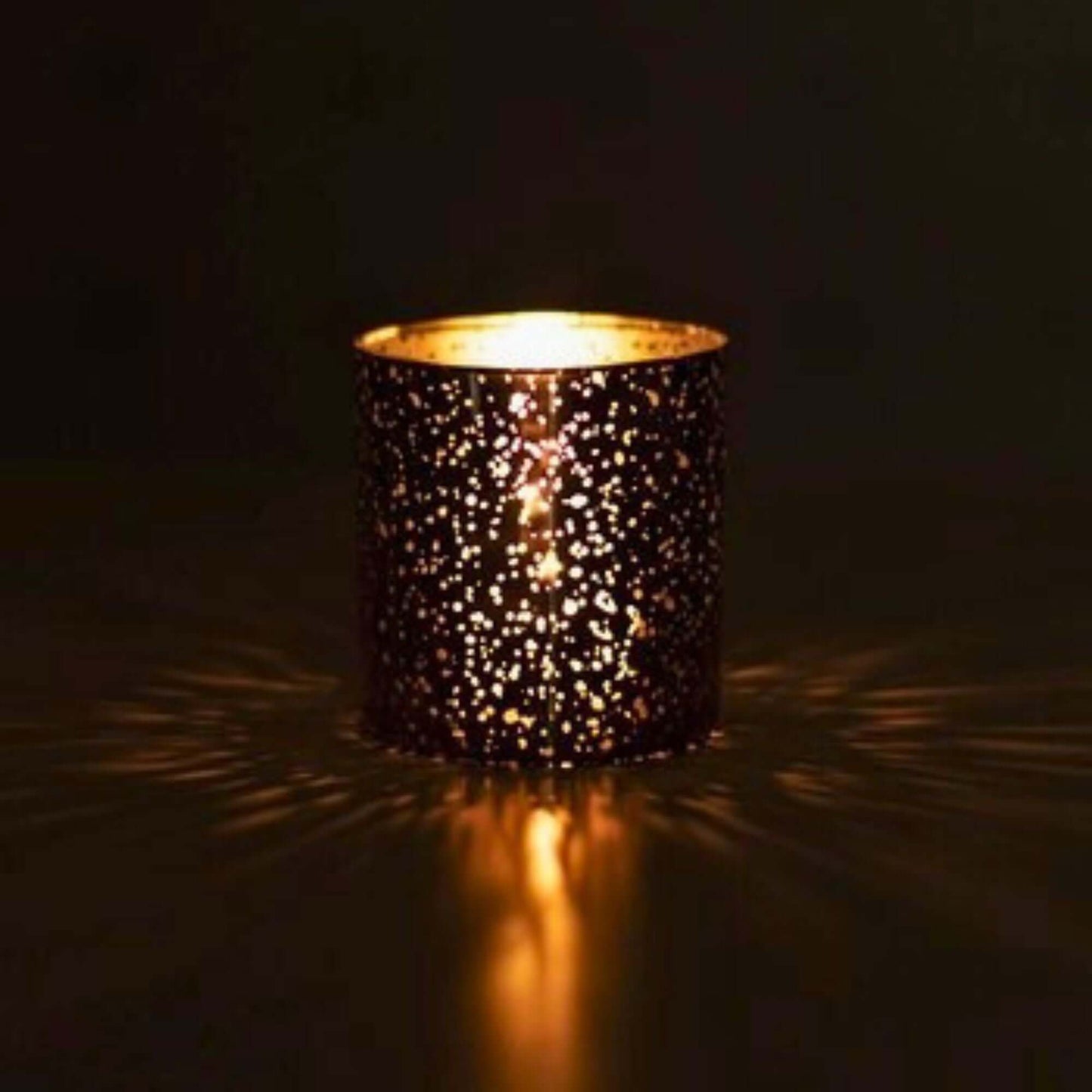 Bergamot & Rosemary candle glowing in the dark with warm light radiating through its gold mercury glass.