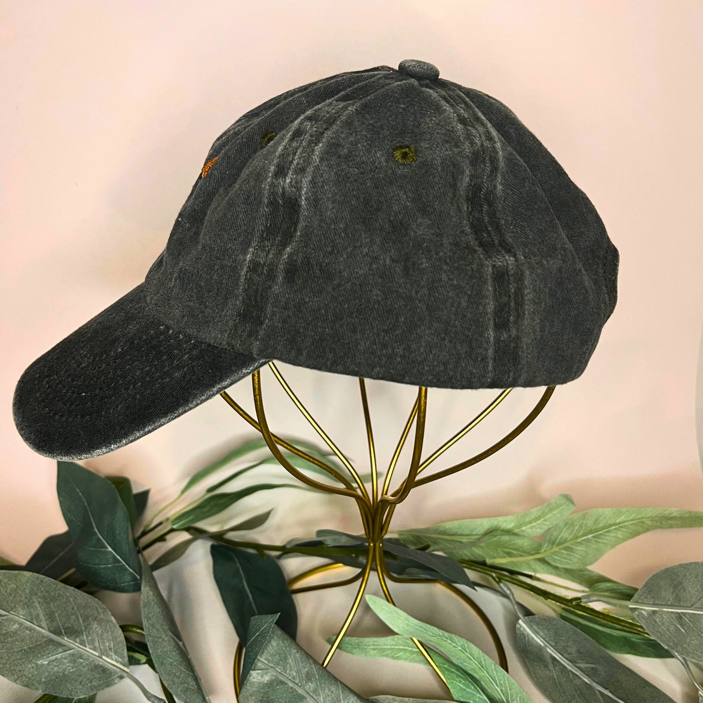 Left side of a green baseball cap with golden poppy embroidery and vintage-inspired washed fabric.
