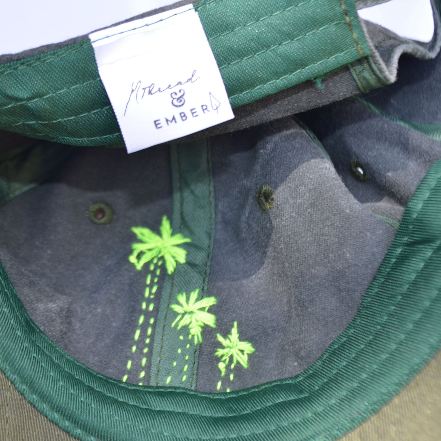 Inside view of green hat with neon palm tree embroidery.