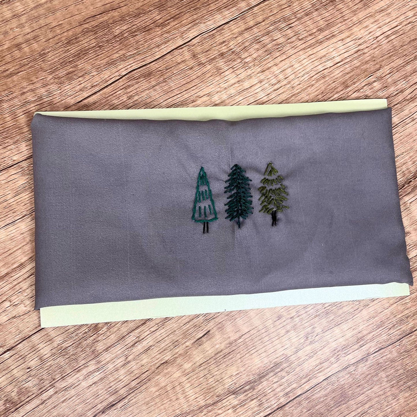 Gray cotton pet bandana with evergreen tree embroidery, displayed flat for detailed design.