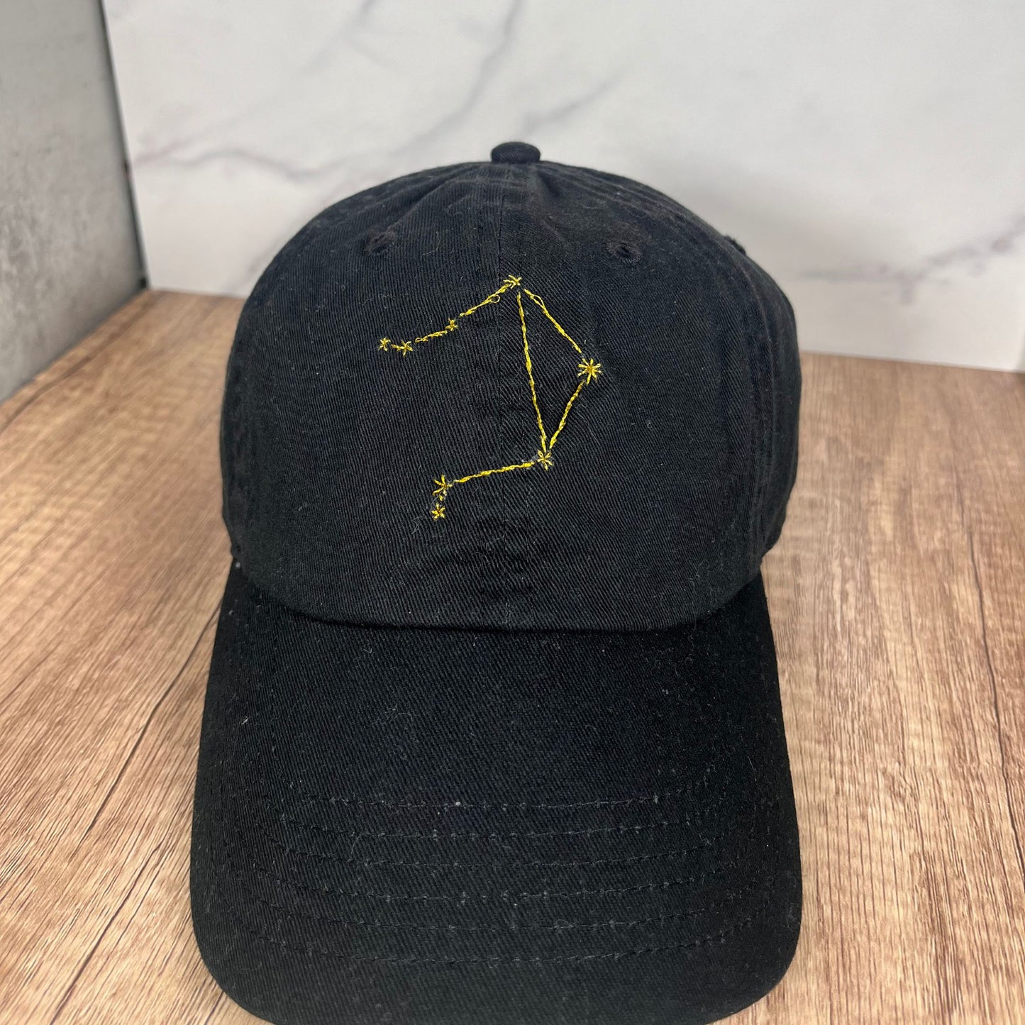 Black dad hat with golden Libra constellation embroidery, front view.