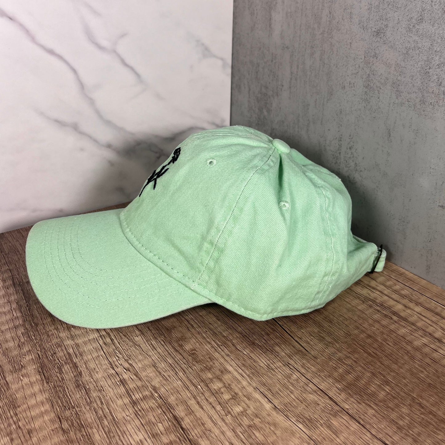 Left-side view of a mint green cap showcasing its sleek and minimal design with adjustable strap at the back.
