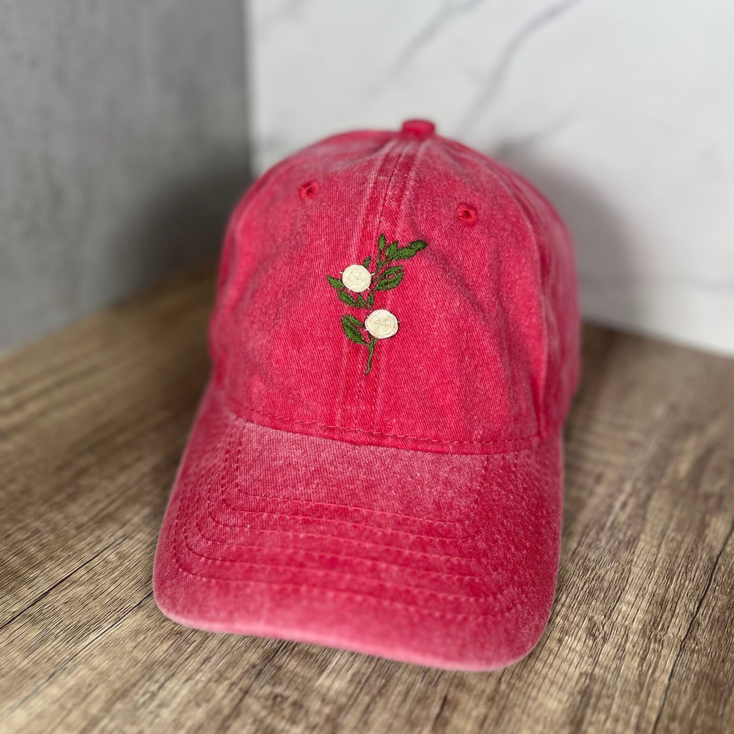 Angled front view of a red distressed dad hat showcasing the embroidered white roses design for a casual and stylish look.