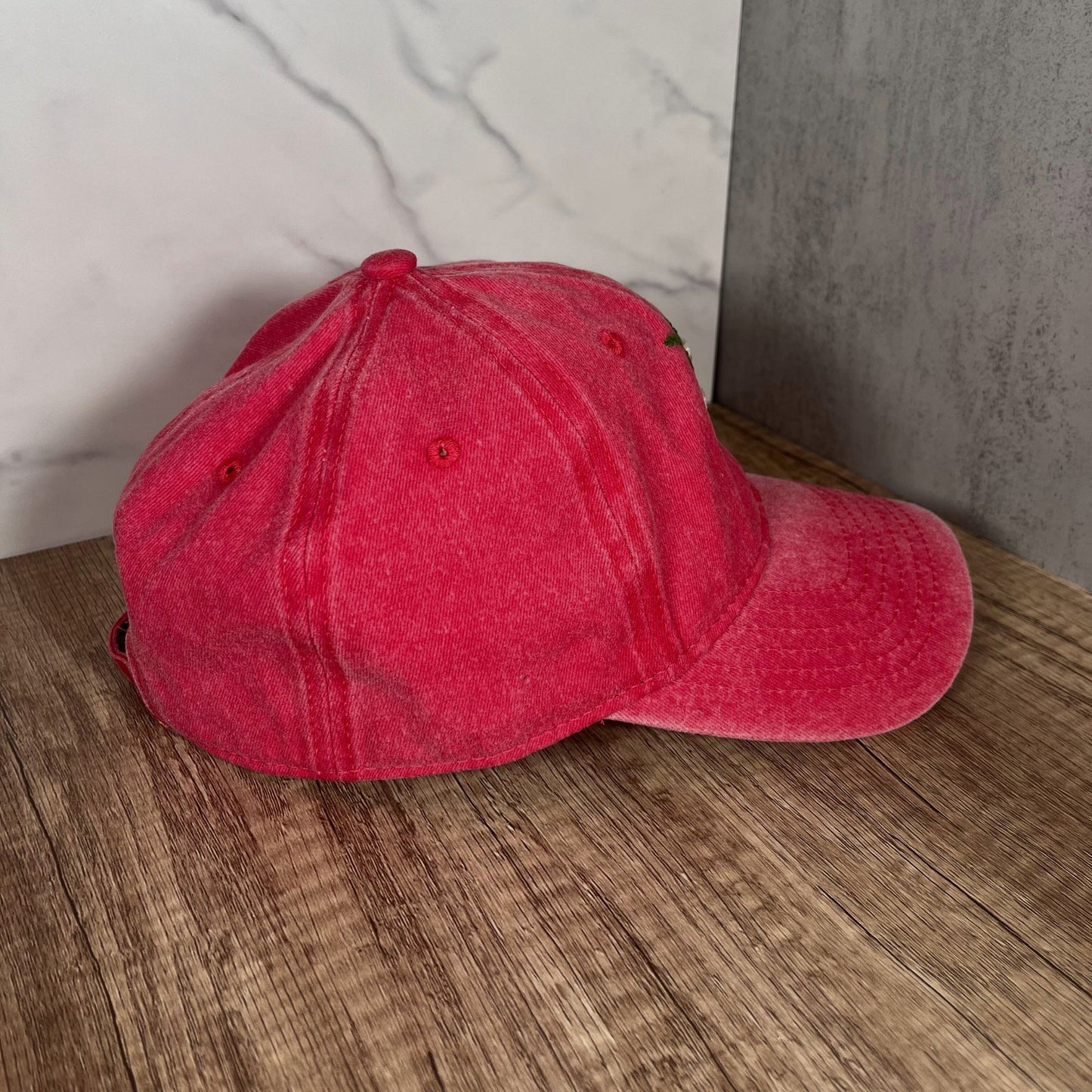 Right side profile of a red dad hat with embroidered white roses, highlighting the curved brim and stitching details.