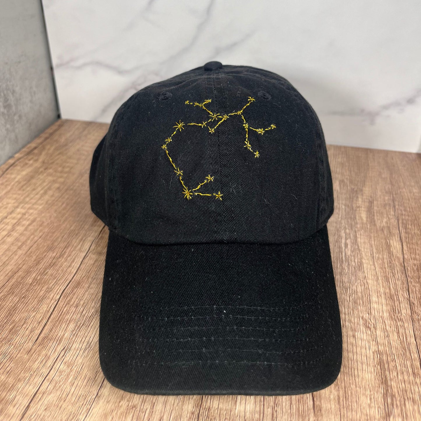 Front view of the black Sagittarius constellation hat, displaying the vibrant yellow embroidered star pattern.