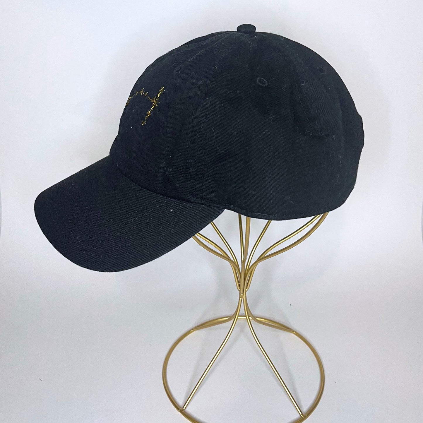 Left side angle of a black Scorpio zodiac embroidered hat displayed on a minimal stand.