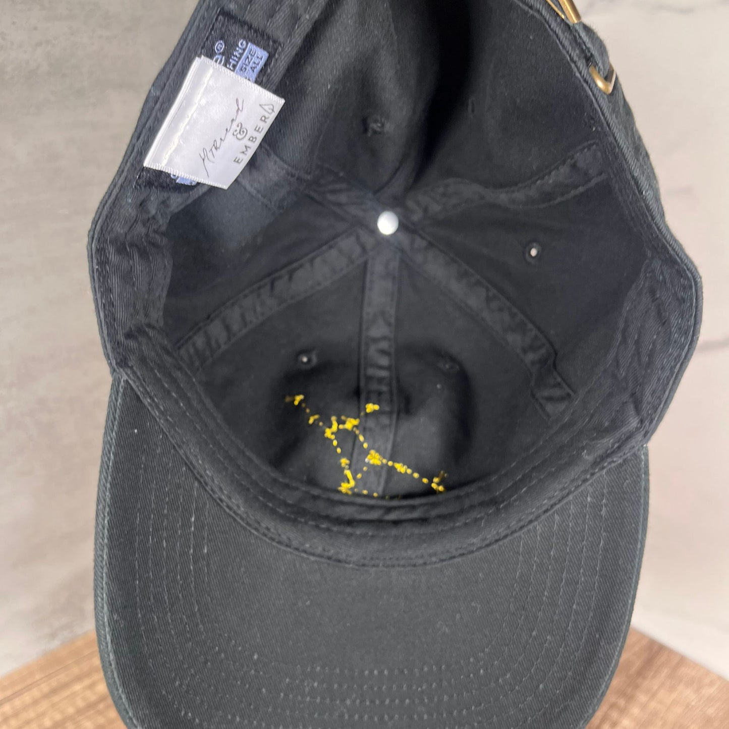 Interior of a black cap showing the Virgo constellation embroidery and the Thread & Ember label.