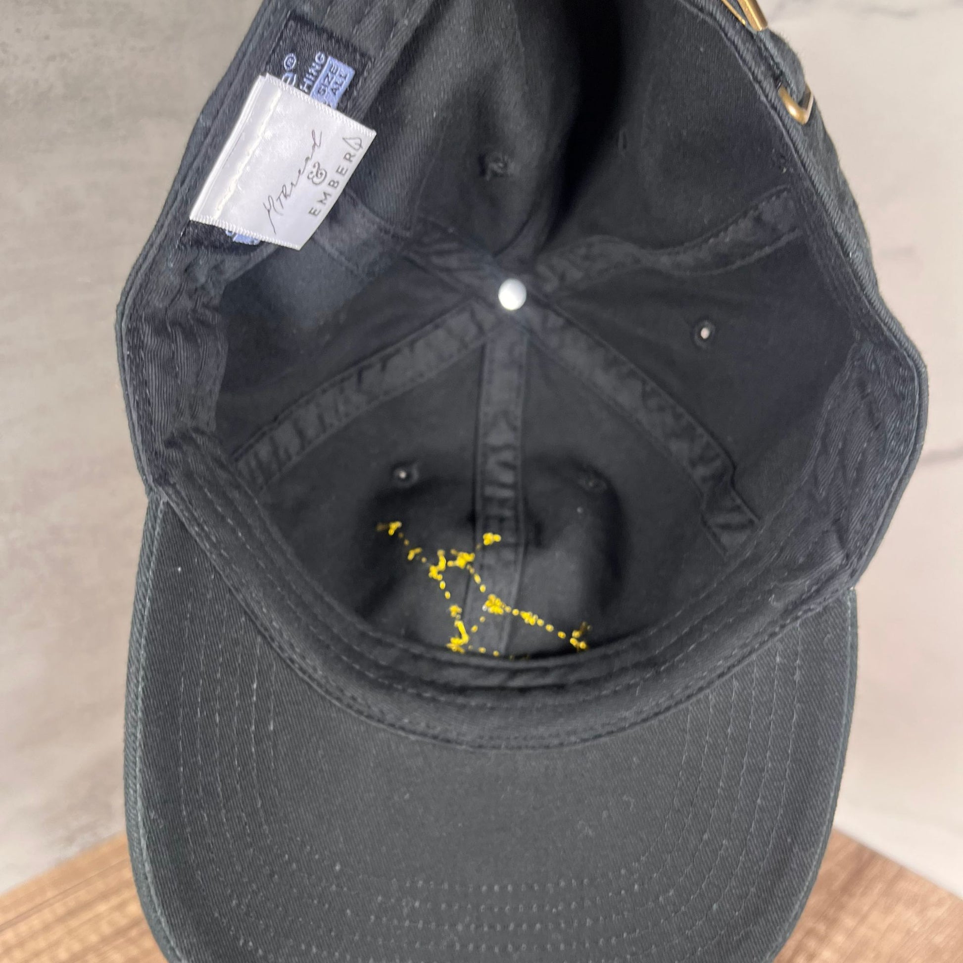 Interior of a black cap showing the Virgo constellation embroidery and the Thread & Ember label.