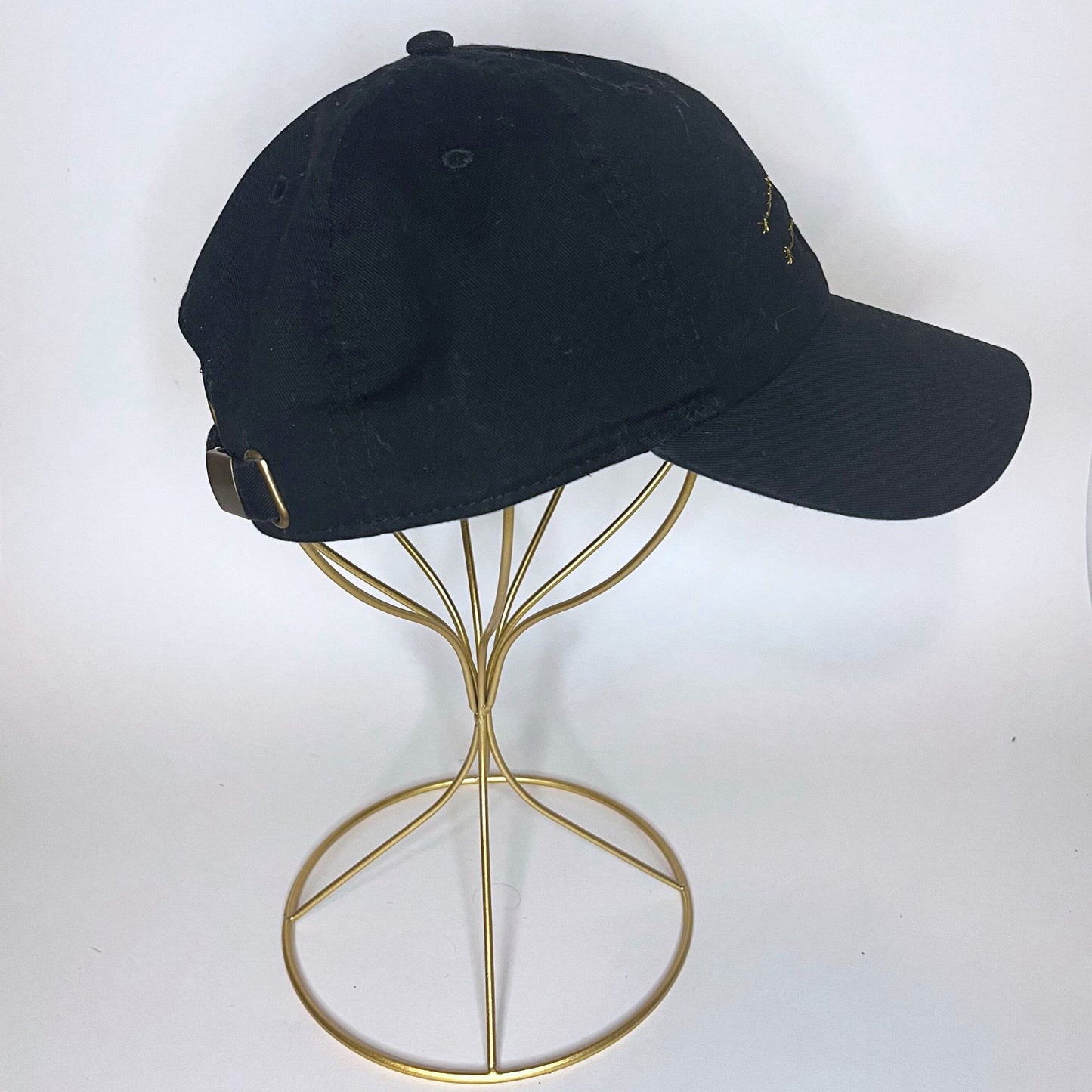 Black cap with Virgo constellation embroidery, showcasing a brass adjustable strap in profile view.