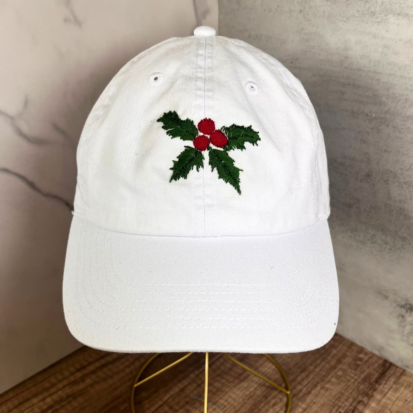 Overhead view of a white hat with hand-embroidered holly and berries for a detailed look.