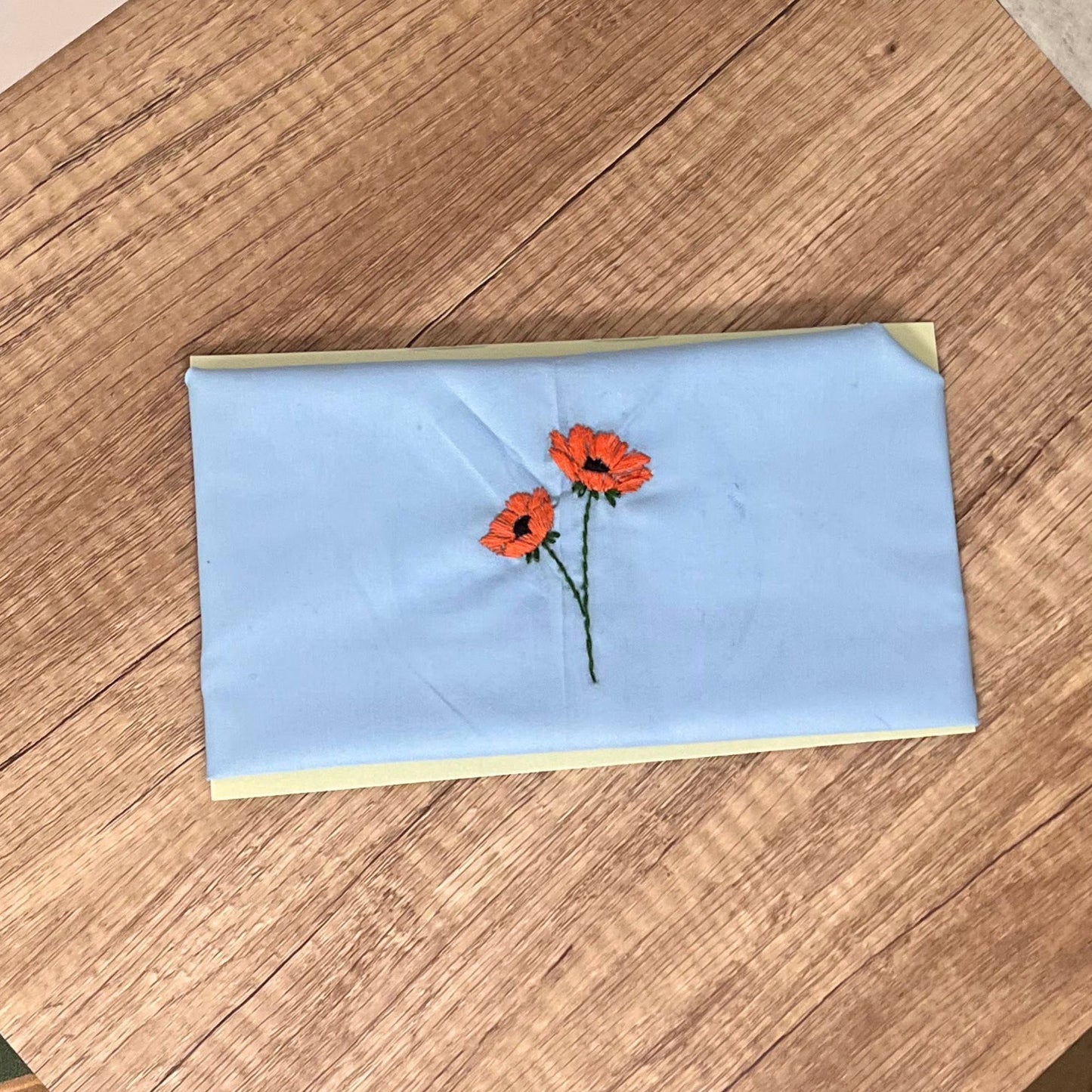 Blue cotton pet bandana with orange poppy embroidery, shown flat for detailed design clarity.