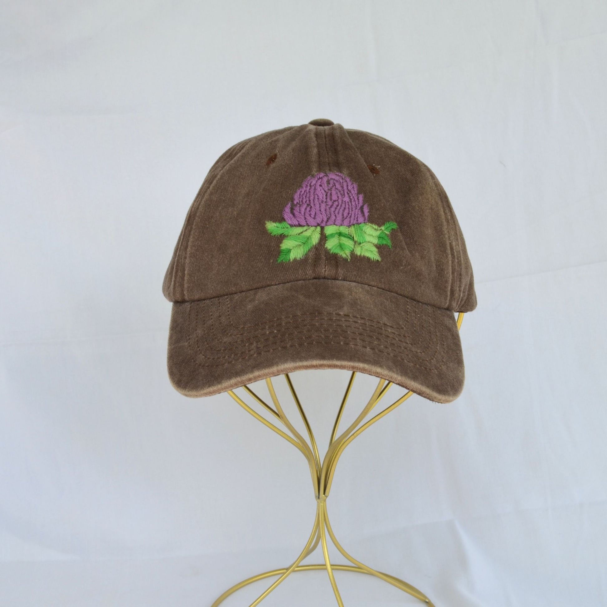 Front view of a brown baseball hat showcasing a detailed artichoke embroidery."