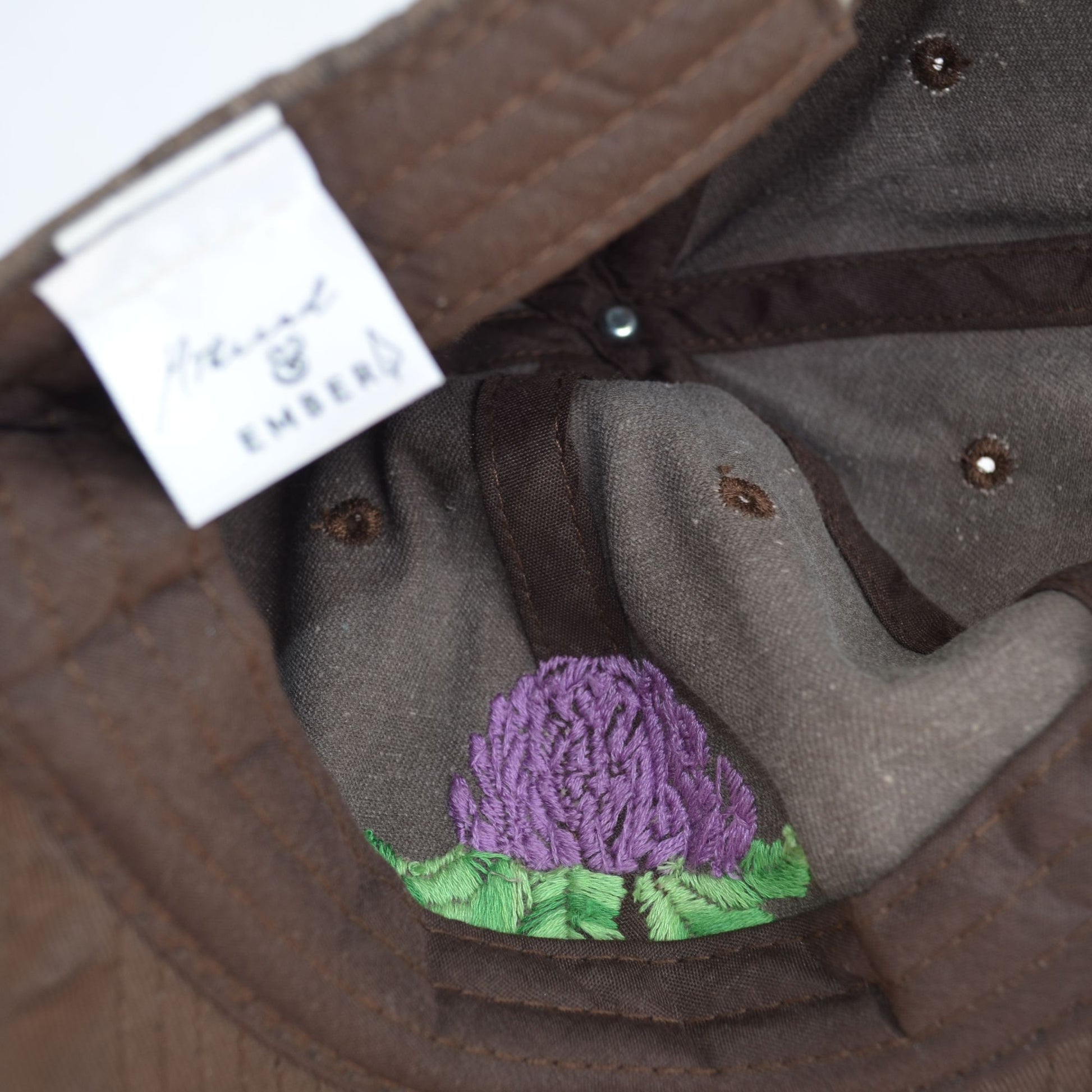 Inside view of a brown baseball hat showing artichoke embroidery details.