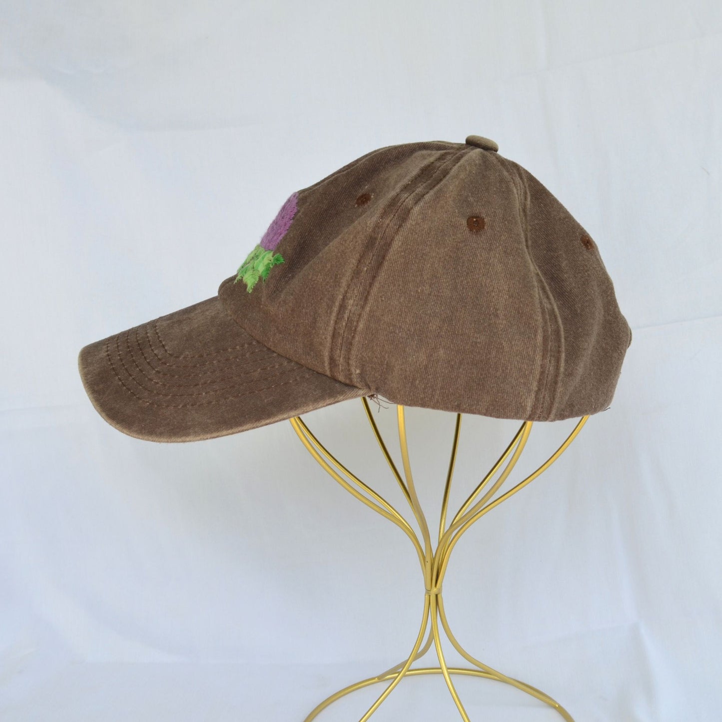 Left side view of a brown baseball hat with artichoke embroidery.