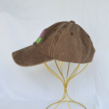 Left side view of a brown baseball hat with artichoke embroidery.