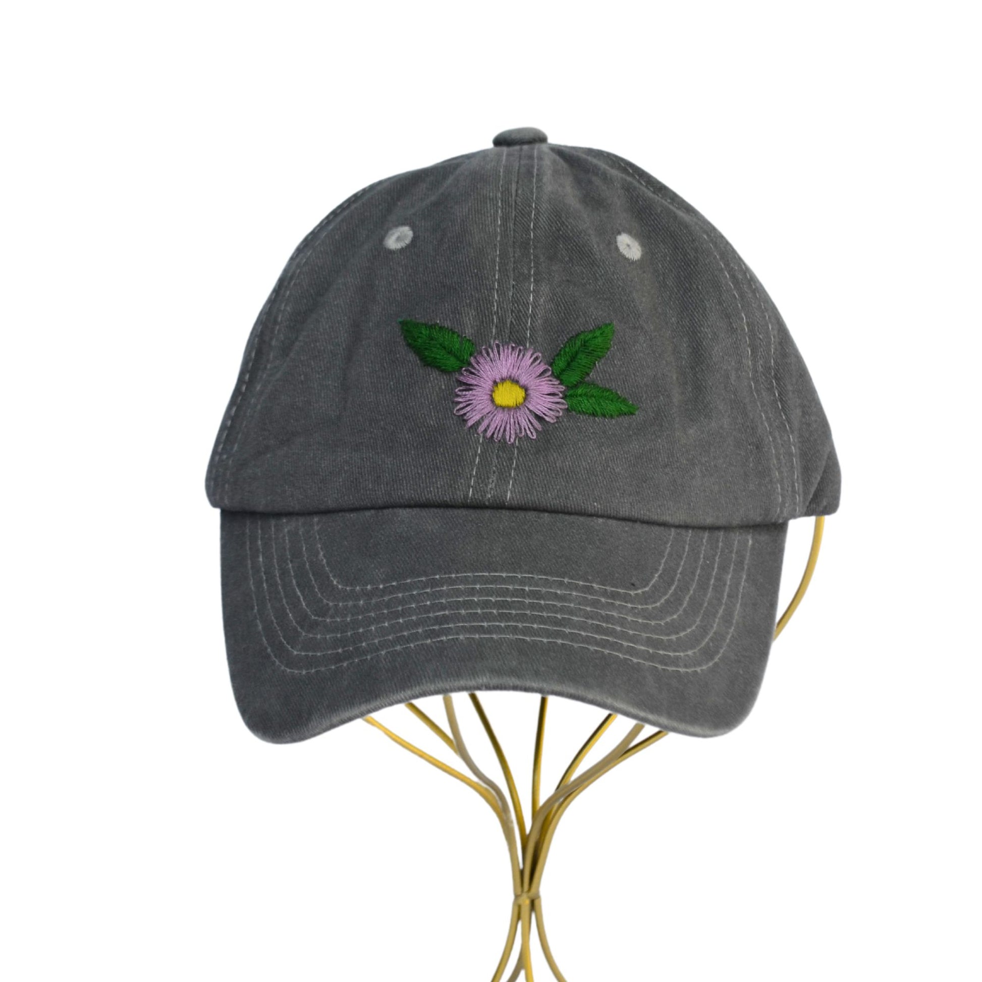 Front view of a grey baseball cap with embroidered gerber daisies and green leaves.